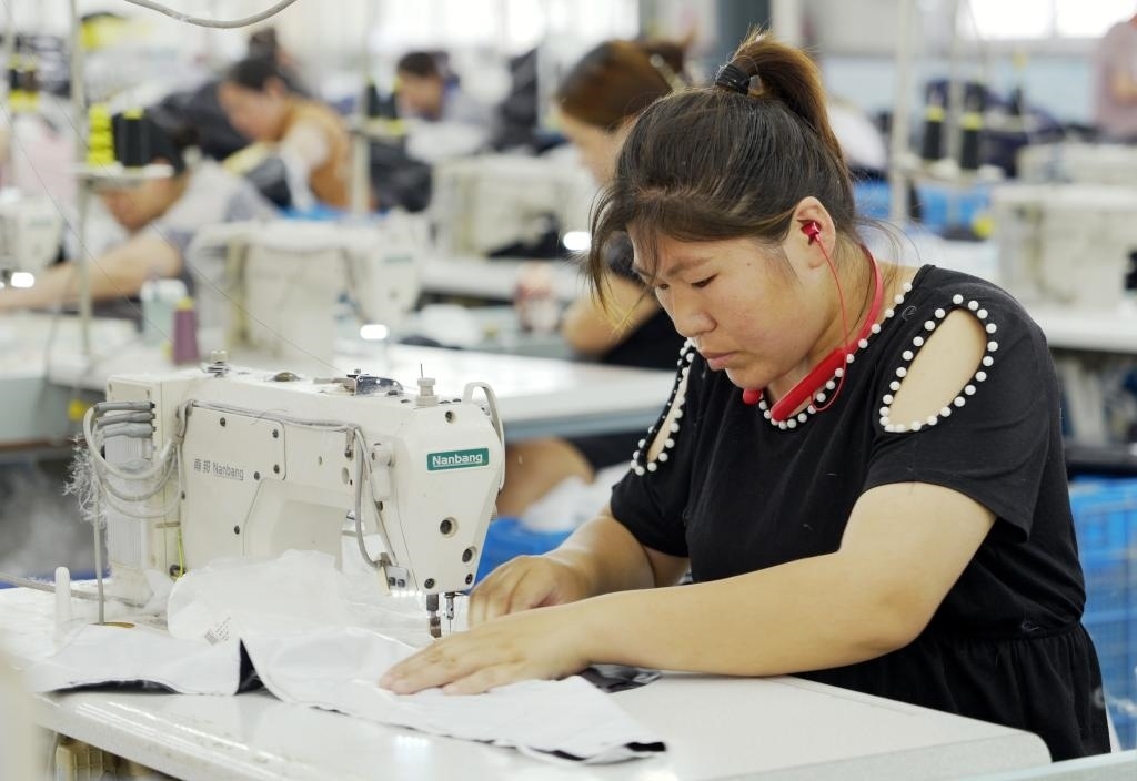 5月20日，村民在李寨村服裝加工廠內(nèi)忙碌。河南省周口市沈丘縣馮營鎮(zhèn)李寨村地處豫東平原。近年來，乘著脫貧攻堅與鄉(xiāng)村振興政策的東風(fēng)，李寨村積極探索產(chǎn)業(yè)發(fā)展模式，通過“龍頭企業(yè)+村集體經(jīng)濟+農(nóng)戶”的方式，逐漸發(fā)展形成肉牛養(yǎng)殖、設(shè)施農(nóng)業(yè)、服裝加工、康養(yǎng)民宿等產(chǎn)業(yè)，以產(chǎn)業(yè)振興助力鄉(xiāng)村振興。新華社記者 李嘉南 攝