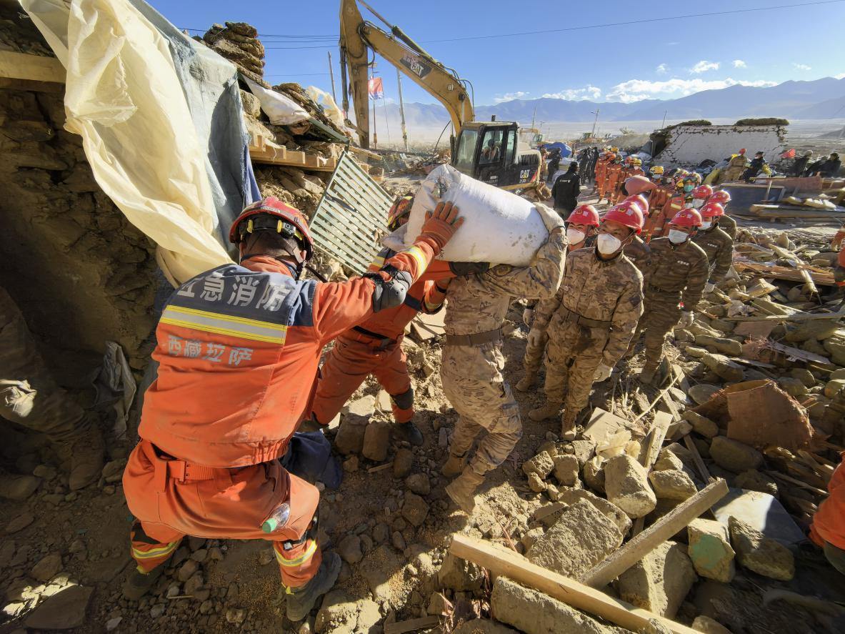 1月11日，定日縣長所鄉(xiāng)古榮村，應(yīng)急消防等救援人員排隊(duì)接力搶運(yùn)掩埋在倒塌房屋下的群眾財(cái)物。人民日報(bào)記者楊翹楚攝