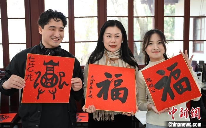 1月20日，外籍留學(xué)生和西泠印社社員李硯(中)展示各自創(chuàng)作的福貼。當(dāng)日，來自巴西、馬來西亞、加納、哈薩克斯坦的外籍留學(xué)生在浙江杭州西泠印社體驗福貼、春聯(lián)和篆刻，感受古老的中國傳統(tǒng)文化。中新社記者 王剛 攝