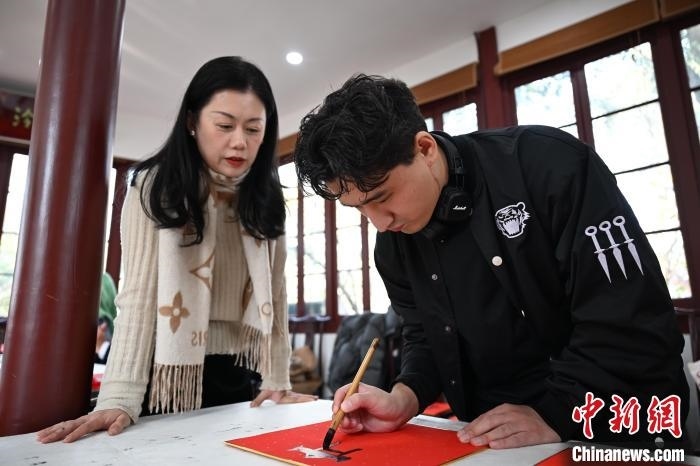 1月20日，外籍留學(xué)生在西泠印社社員李硯指導(dǎo)下寫福。當(dāng)日，來自巴西、馬來西亞、加納、哈薩克斯坦的外籍留學(xué)生在浙江杭州西泠印社體驗福貼、春聯(lián)和篆刻，感受古老的中國傳統(tǒng)文化。中新社記者 王剛 攝