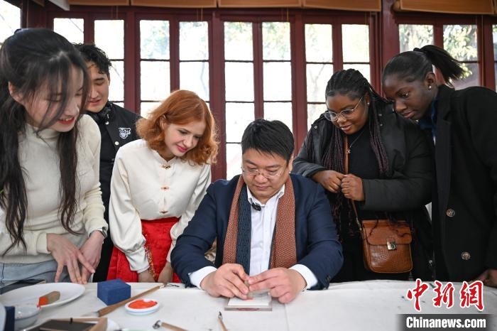 1月20日，篆刻家王臻向外籍留學(xué)生展示篆刻印章。當(dāng)日，來自巴西、馬來西亞、加納、哈薩克斯坦的外籍留學(xué)生在浙江杭州西泠印社體驗福貼、春聯(lián)和篆刻，感受古老的中國傳統(tǒng)文化。中新社記者 王剛 攝