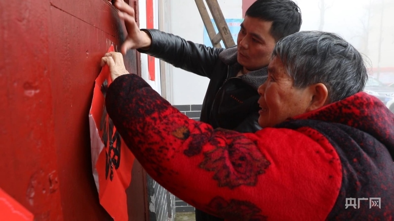 彭德良與70多歲母親貼春聯(lián)（央廣網(wǎng)記者 郇康新 攝）