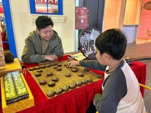 柯秋楓與市民下椰雕象棋。人民網 陳葉欣攝