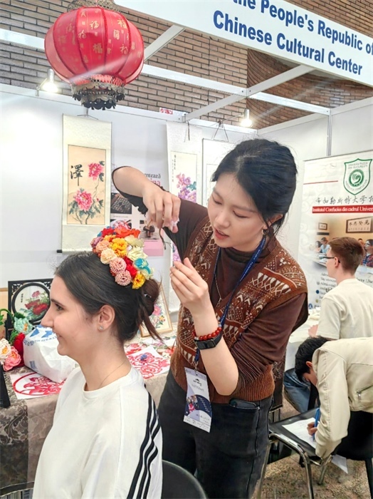 展覽正值羅馬尼亞迎春花節(jié)，國(guó)際中文教師志愿者潘婧穎向游客們介紹了國(guó)家非物質(zhì)文化遺產(chǎn)——福建泉州的簪花文化。布加勒斯特大學(xué)孔子學(xué)院供圖。