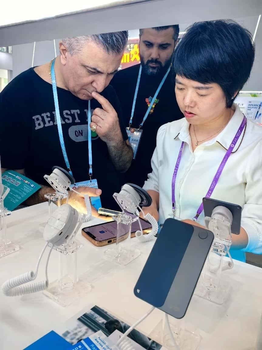 展臺(tái)工作人員向外商展示“AI TOP翻譯終端”。圖片來(lái)源：受訪者提供