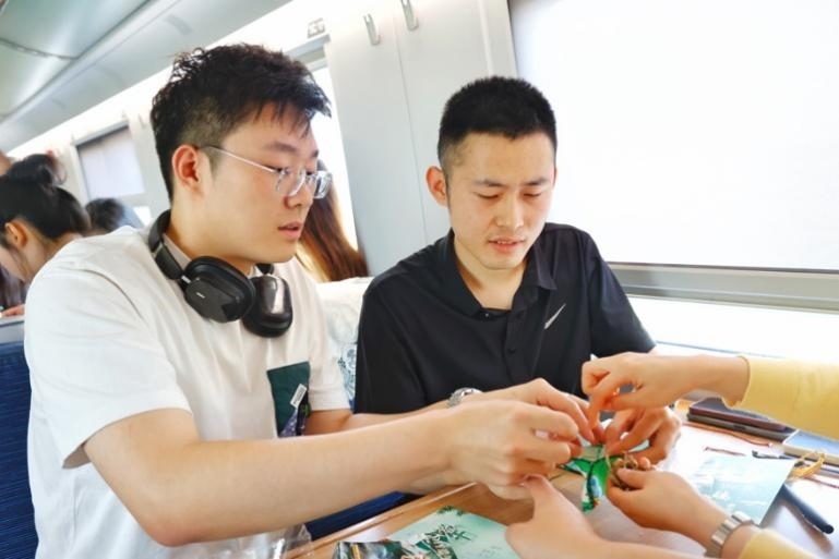 G232次旅客親手制作端午荷包和五彩繩。王磊攝
