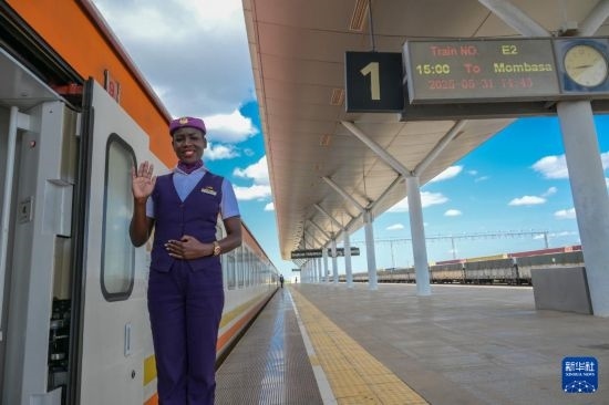 5月31日，在蒙內(nèi)鐵路內(nèi)羅畢站，一名乘務(wù)員在即將開往蒙巴薩的E2次列車旁等候乘客。新華社記者 楊光 攝