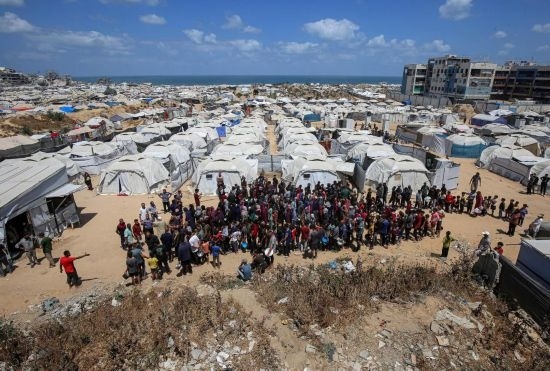 5月28日，人們?cè)诩由吵俏鞑康纳程犭y民營(yíng)等待領(lǐng)取救助食物。新華社發(fā)（里澤克·阿卜杜勒賈瓦德攝）